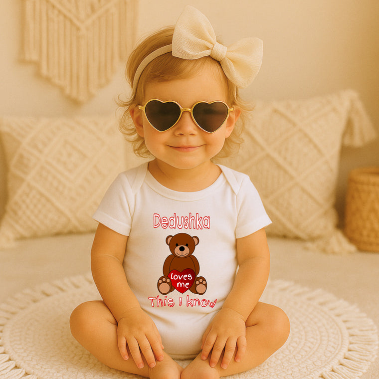 A young girl wearing a white t-shirt with a teddy bear graphic and heart-shaped sunglasses, sitting on a white rug.