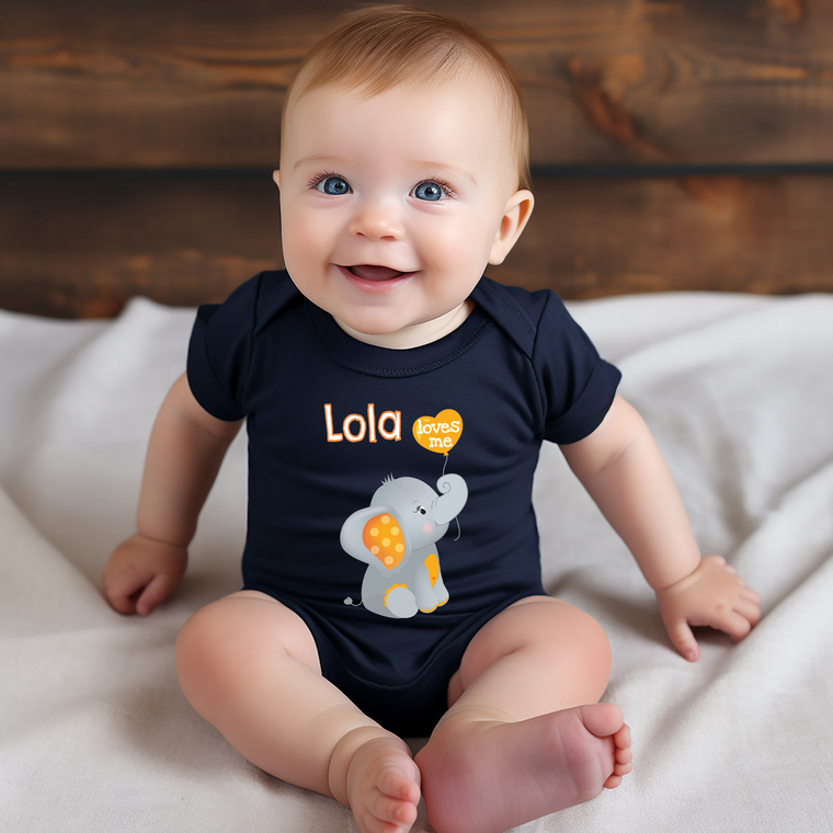 A smiling baby boy wearing a black shirt with an elephant design sits on a white blanket.