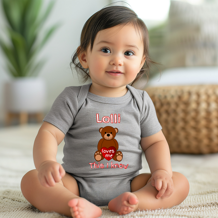 A smiling baby girl wearing a gray onesie with a teddy bear graphic and text.