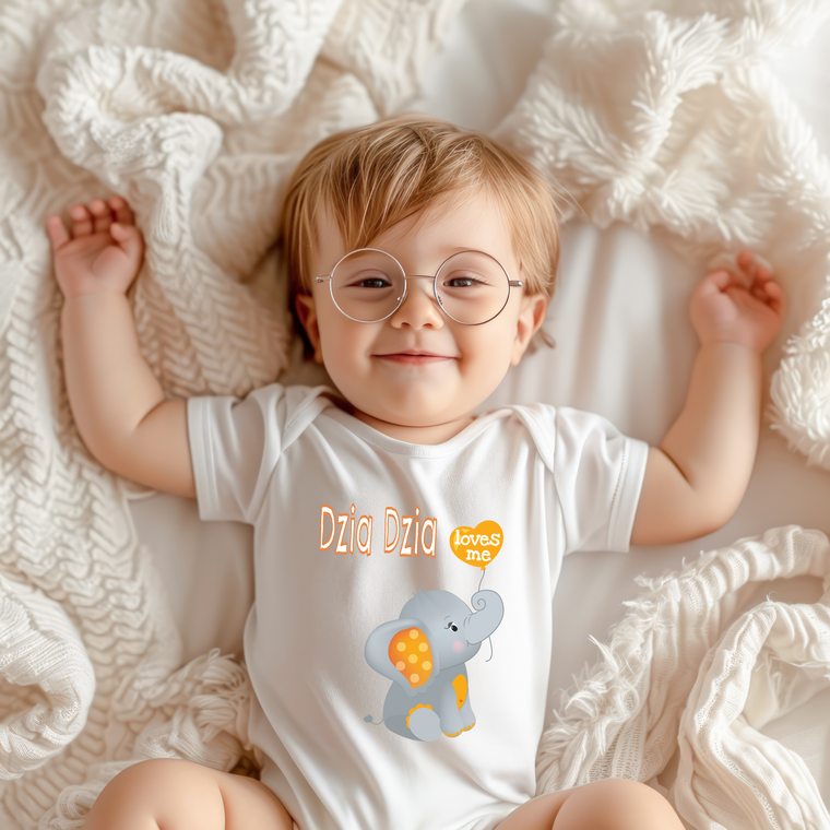 A smiling baby wearing a white onesie with an elephant graphic lies on a white blanket.