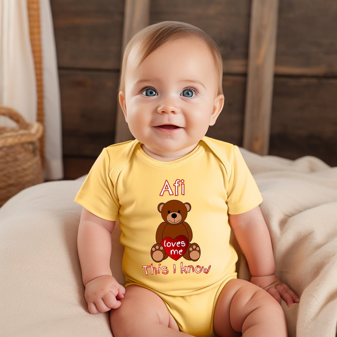 A smiling baby wearing a yellow onesie with a teddy bear graphic and text.