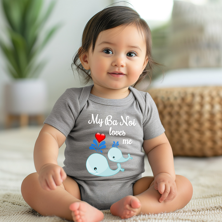 A smiling baby girl wearing a gray onesie with a graphic of a whale and the text "My Ba Not loves me" is sitting on the floor.
