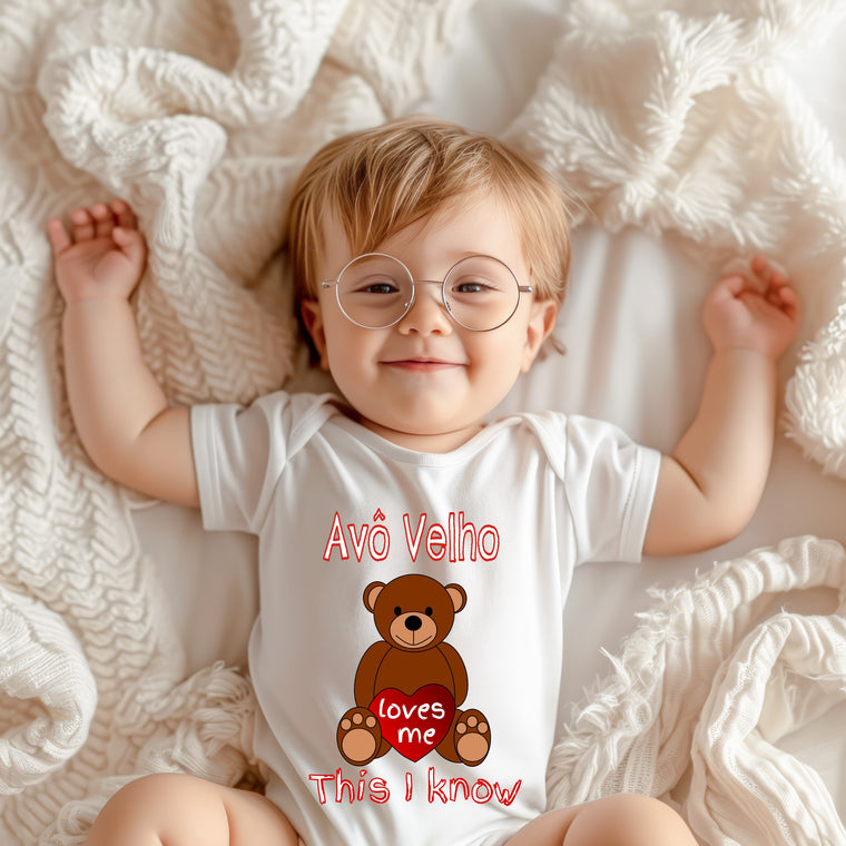 A smiling baby wearing a white onesie with a teddy bear graphic and text.