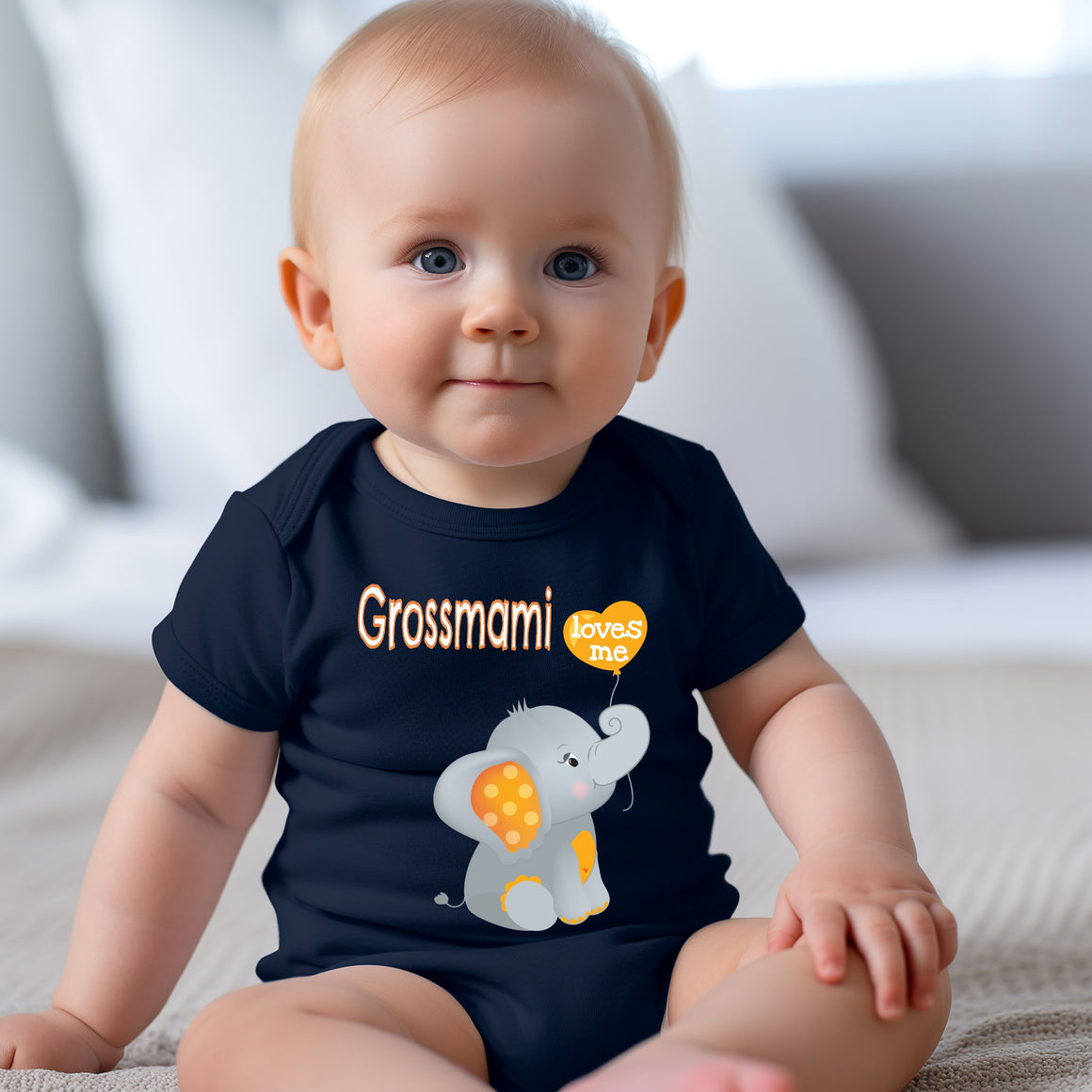 A smiling baby boy wearing a navy blue t-shirt with an elephant graphic and the text "Grossmann loves me" printed on it.