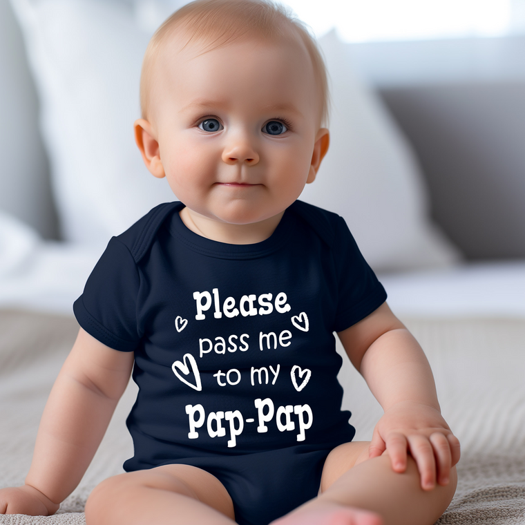 A smiling baby wearing a navy blue onesie with the text "Please pass me to my Pap-Pap" printed on it.