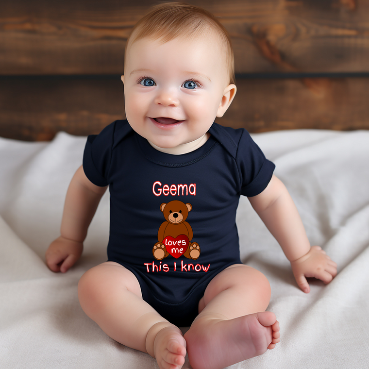 A smiling baby wearing a navy blue onesie with a teddy bear graphic and text that says "Geme loves me This I know".