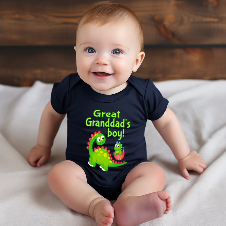 A smiling baby wearing a black shirt with a dinosaur graphic and text that says "Great Grandpa's boy!"