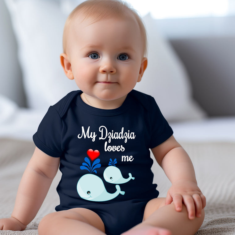 A smiling baby wearing a navy blue t-shirt with a graphic of a whale and the text "My Dzidzia loves me" printed on it.