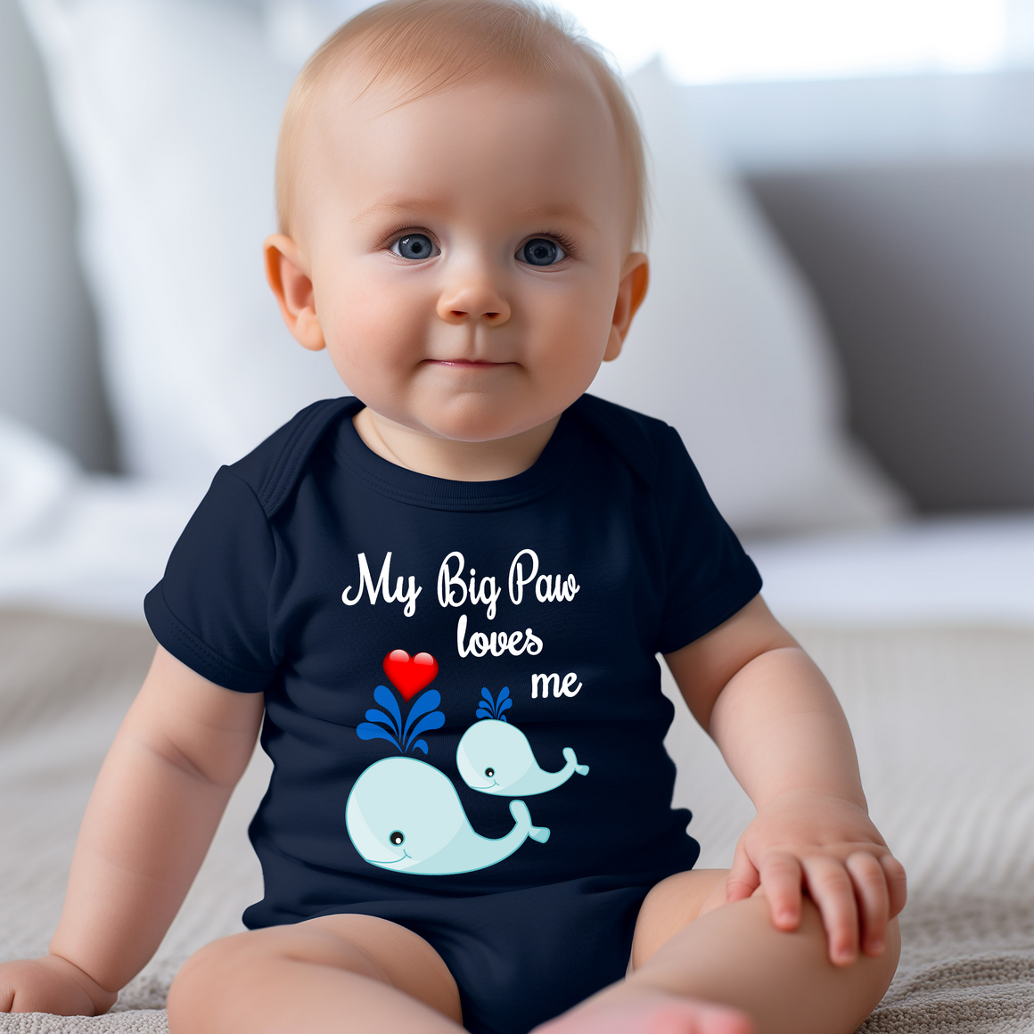 A smiling baby wearing a navy blue t-shirt with a cartoon whale and the text "My Big Paw loves me" printed on it.