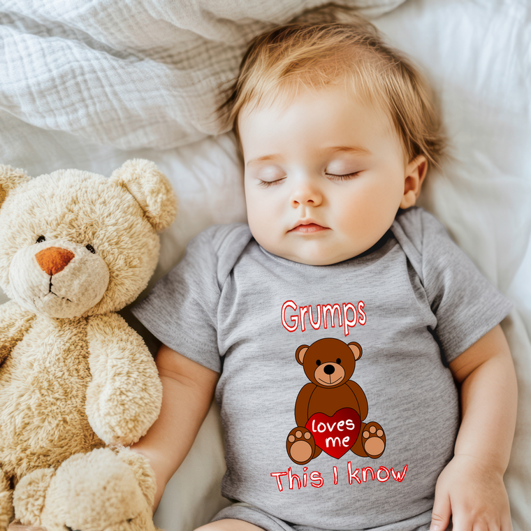 A sleeping baby wearing a gray shirt with a teddy bear and the text "Grumps loves me This I know" is shown in the image.