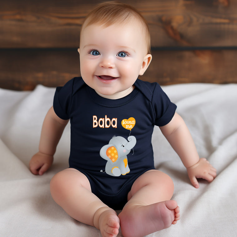 A smiling baby wearing a black shirt with an elephant design sits on a white blanket.