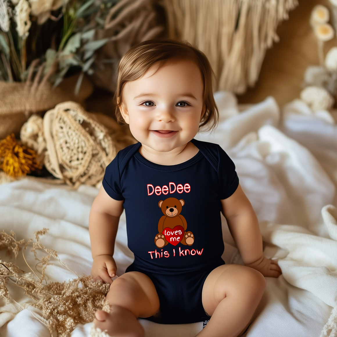 A smiling baby boy wearing a navy blue onesie with a teddy bear design and text on it.