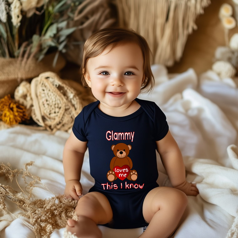 A smiling baby wearing a navy blue onesie with a teddy bear design and text on it.