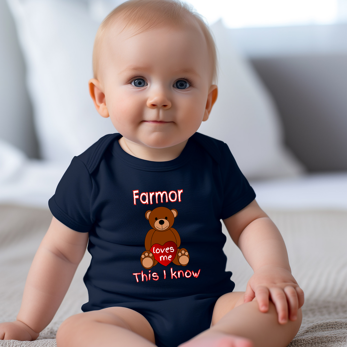 A smiling baby wearing a navy blue t-shirt with a teddy bear graphic and text.