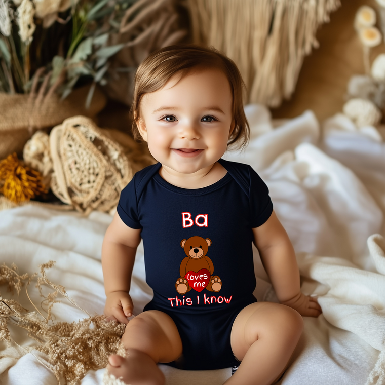 A smiling baby wearing a navy blue onesie with a teddy bear design and text on it.