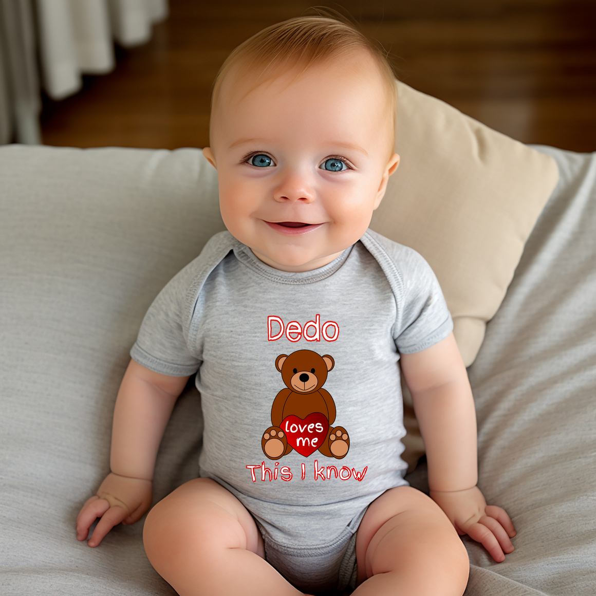 A smiling baby wearing a gray onesie with a teddy bear graphic and text.