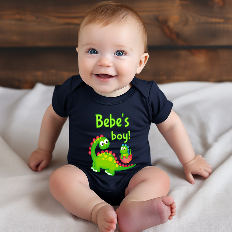 A smiling baby wearing a black t-shirt with a dinosaur graphic and the text "Bebe's boy!"