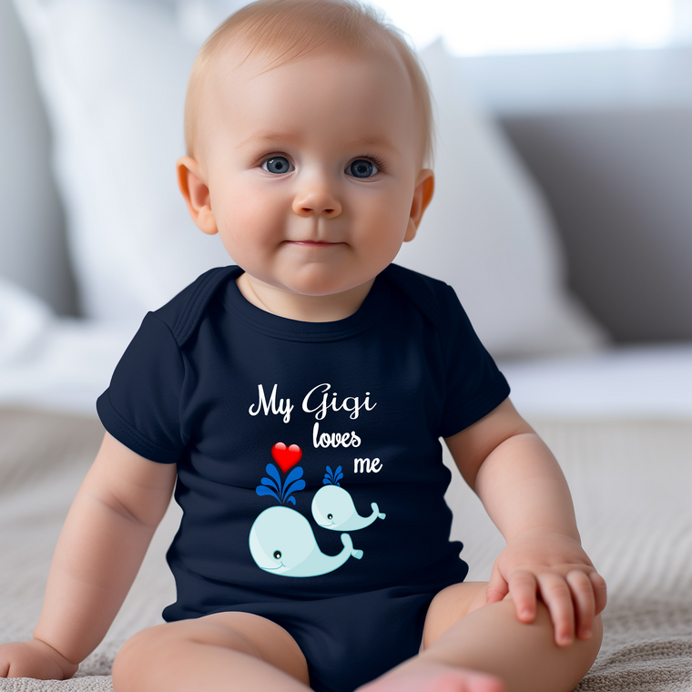 A smiling baby wearing a navy blue t-shirt with a whale graphic and the text "My Gigi loves me" printed on it.
